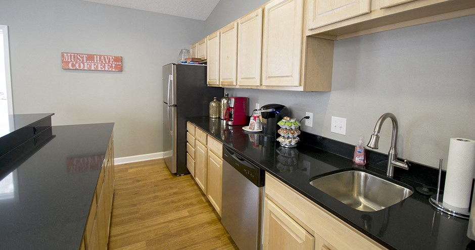 a kitchen with black countertops and a stainless steel refrigerator