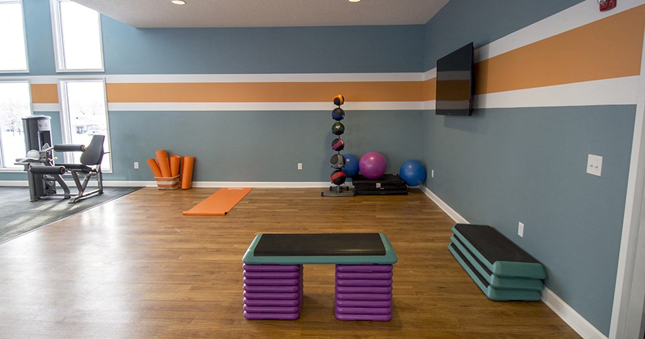 a workout room with a yoga bench and a tv on the wall