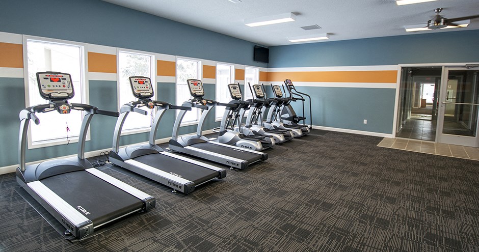 a gym with cardio equipment and a row of exercise machines