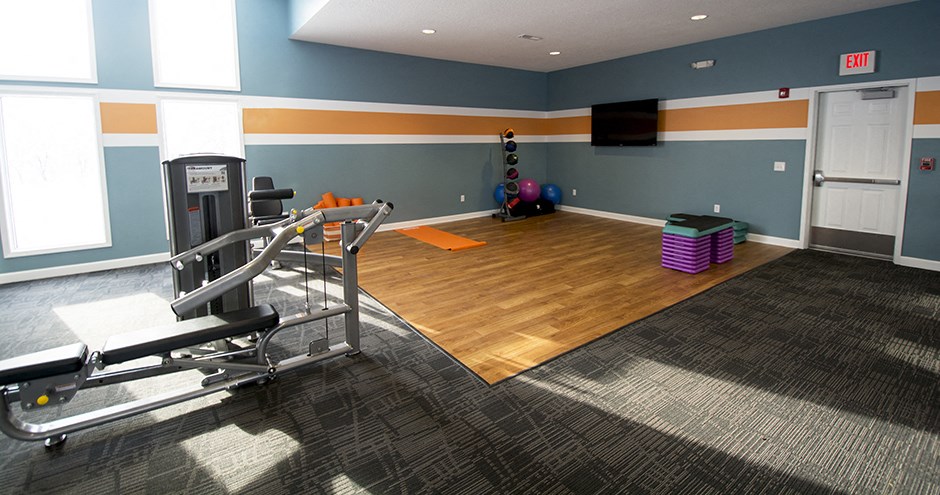 a gym with a reformer and weights on a wooden floor