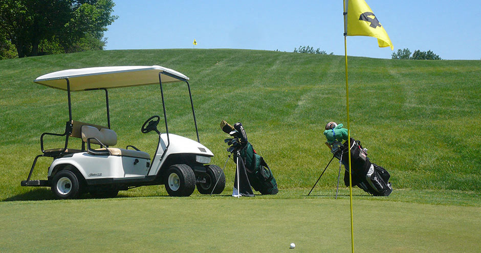 two golfers are standing next to a golf cart