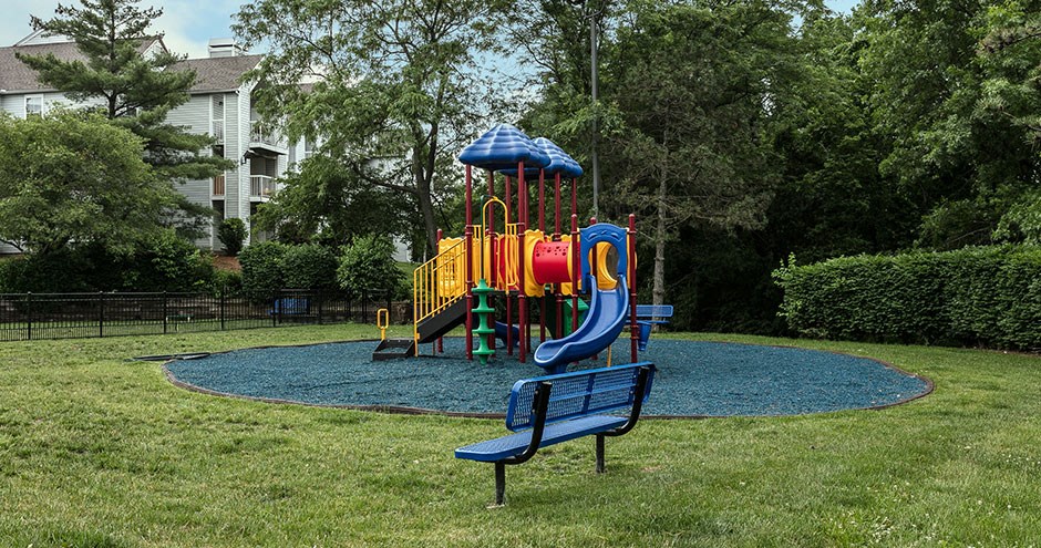 a playground in a park with a blue bench