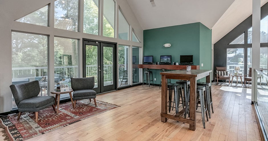 a living room with a bar with chairs and a large window