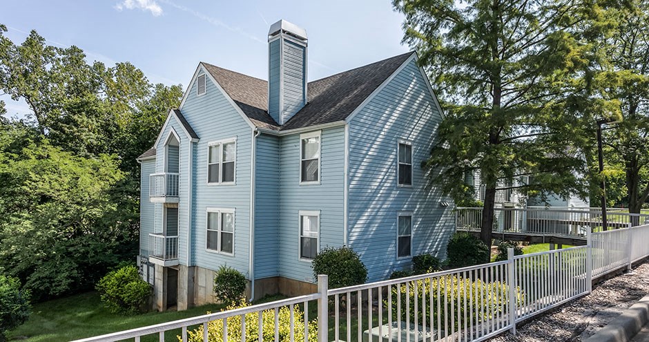 a blue house with a white fence in front of it