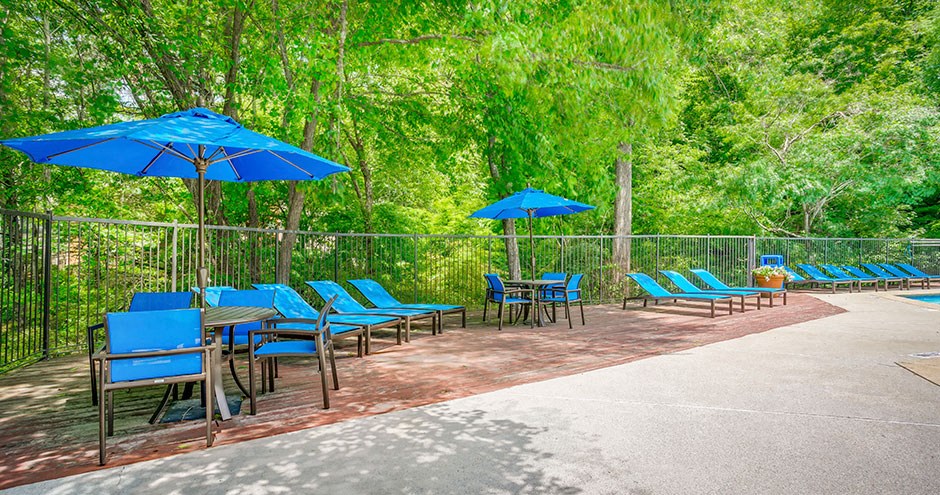 a patio with blue chairs and umbrellas and benches