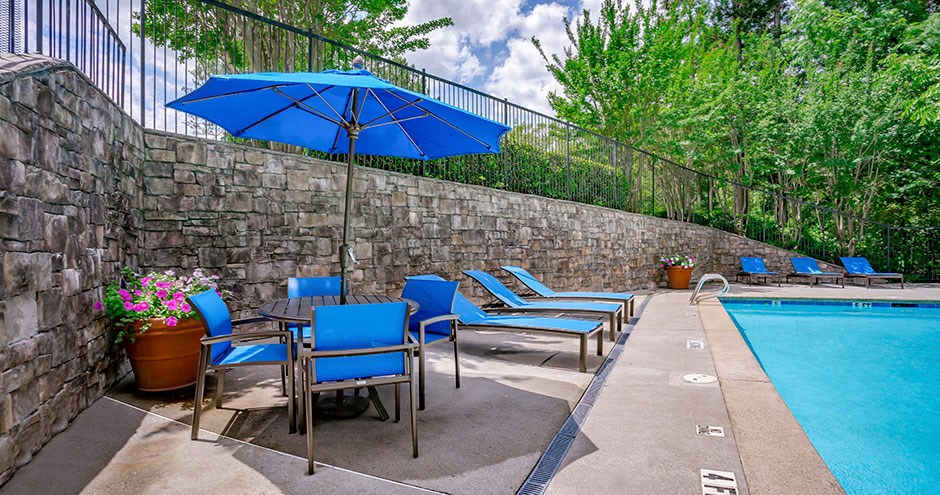 a pool table with chairs and an umbrella next to a pool