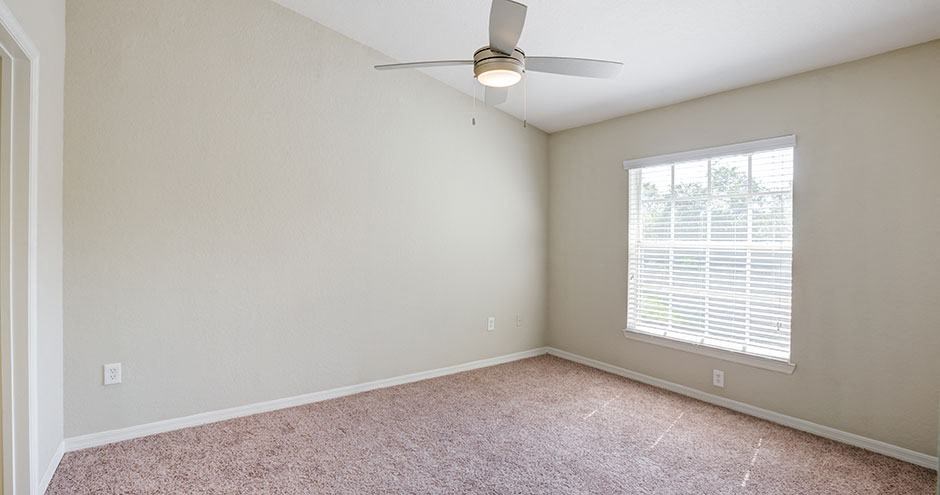 an empty room with a ceiling fan and a window