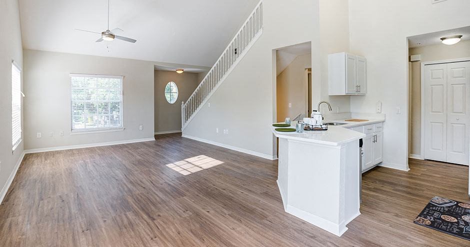 an empty living room with a kitchen and a staircase