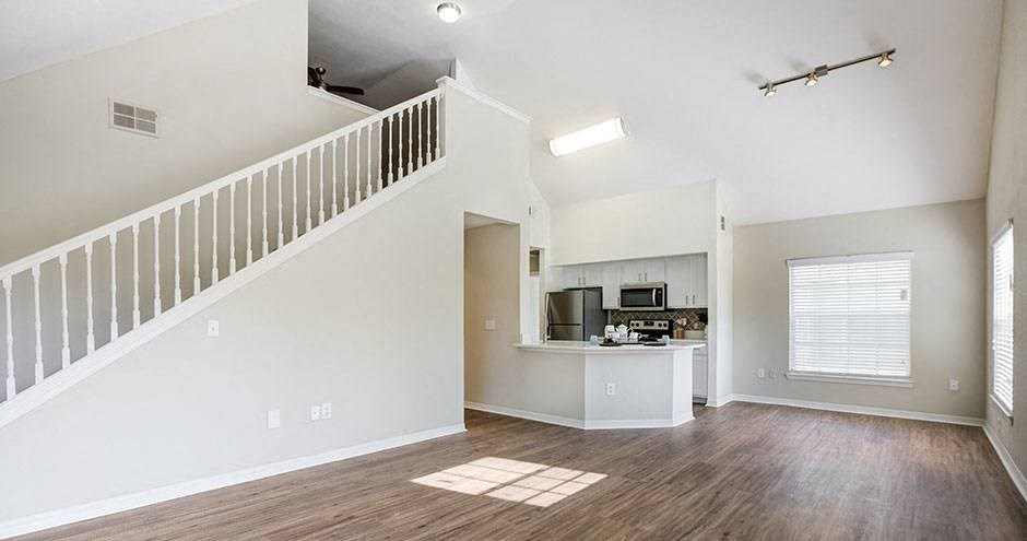 an empty living room and kitchen with a staircase