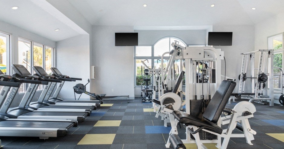 a gym with cardio equipment and windows in a building