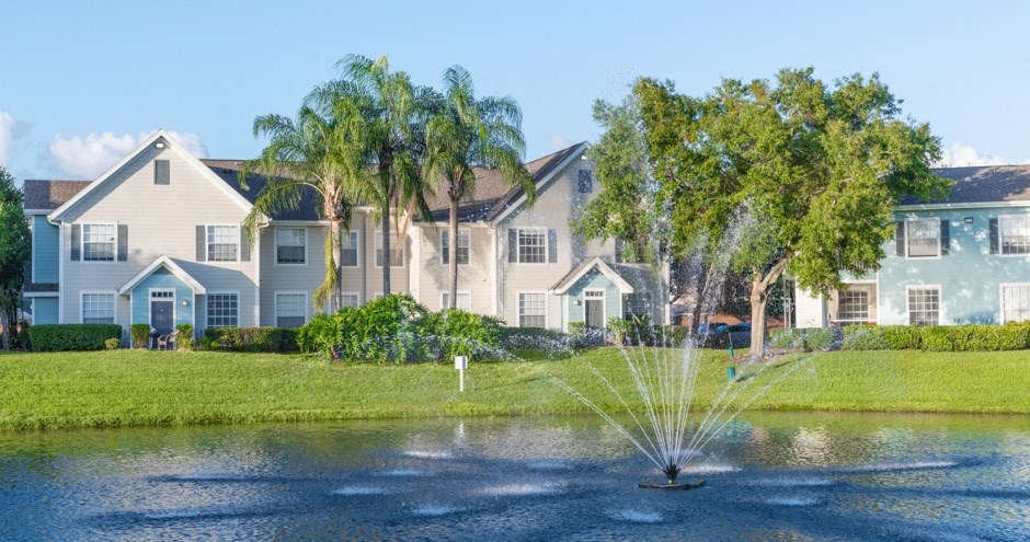 a fountain in a pond in front of houses