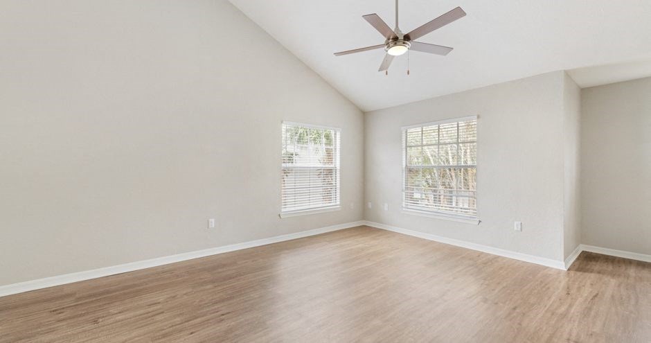 an empty living room with wood floors and a ceiling fan