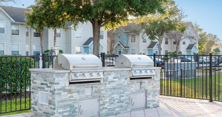 a stone outdoor grill with two bbqs in front of some houses