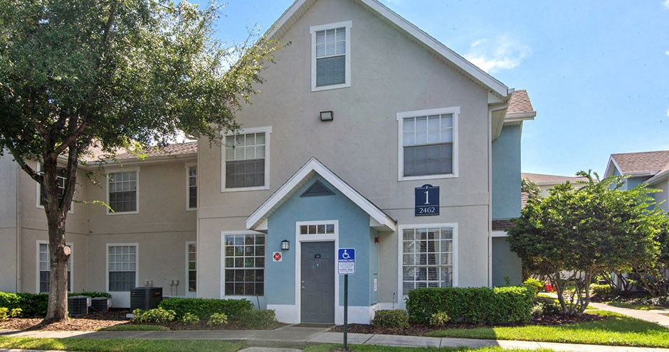 an apartment building with a sidewalk and tree in front of it