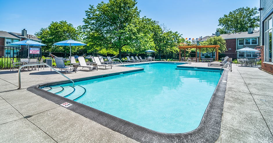 a swimming pool with chairs and umbrellas near a building