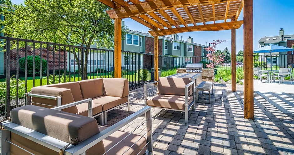 a patio with chairs and a wooden pergola
