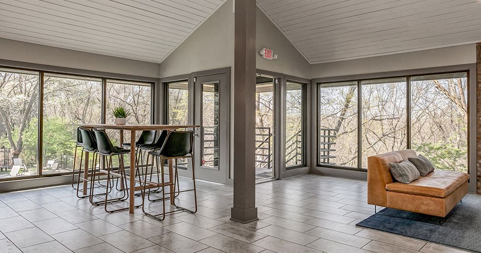 a living room with a bar with chairs and a view of trees