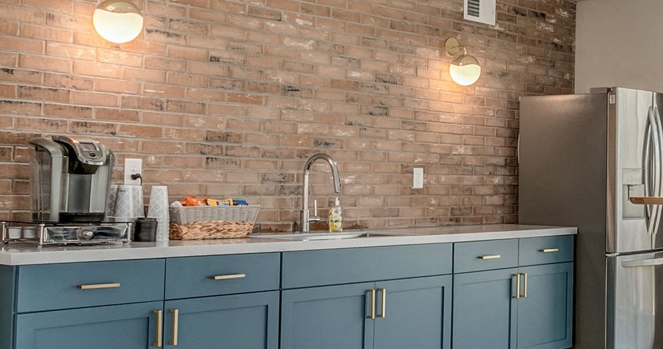 a kitchen with blue cabinets and a brick wall