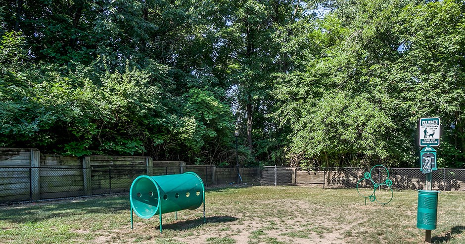 a green tank in a park next to a fence