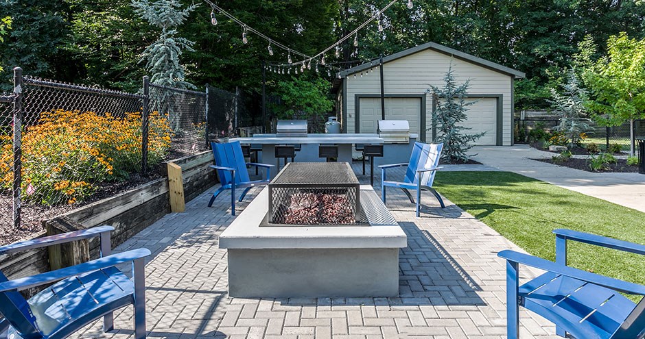 a patio with a fire pit and chairs and a table