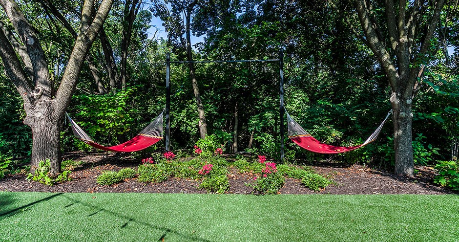 two hammocks in a garden with flowers and trees