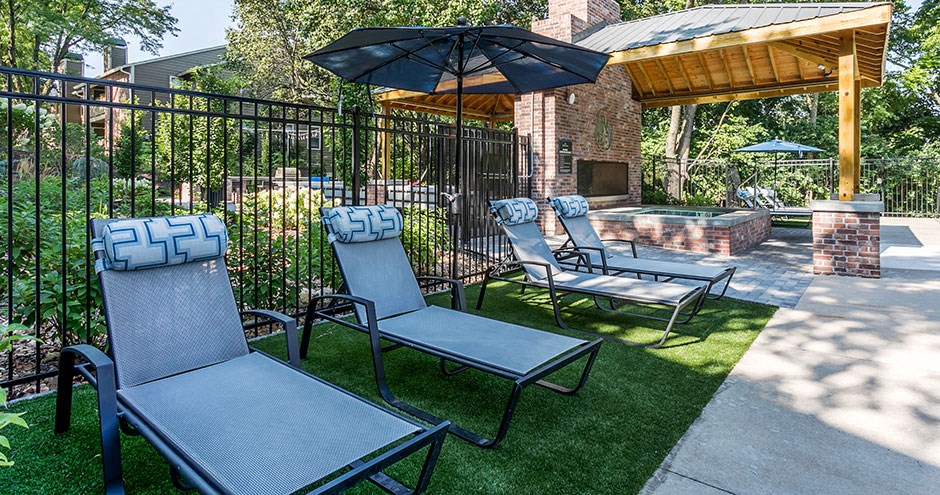 a patio with chairs and an umbrella and a grill