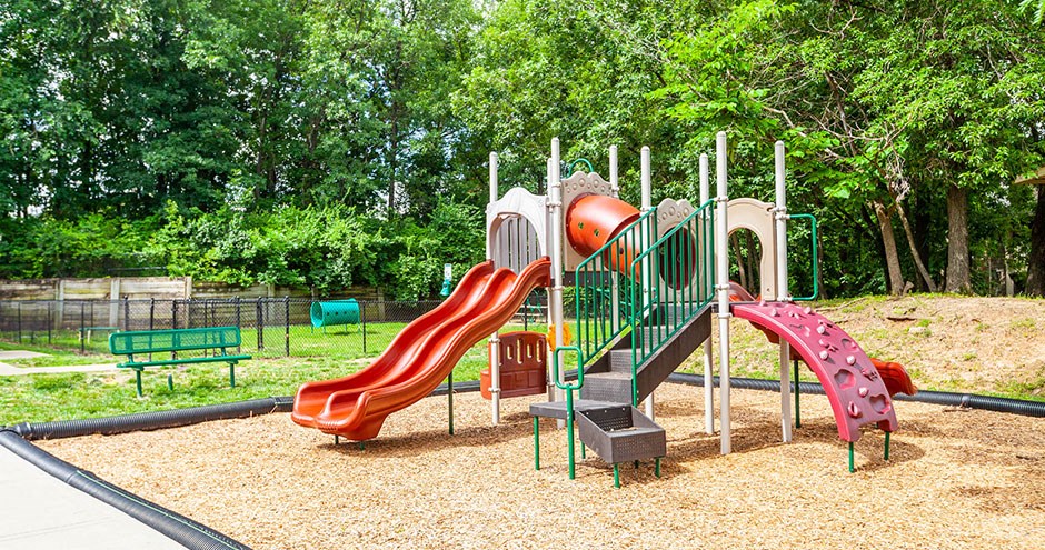 a playground with slides and benches in a park