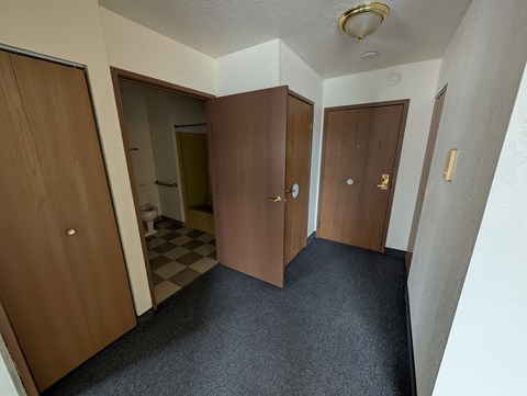 A hallway with three doors and a checkered floor.