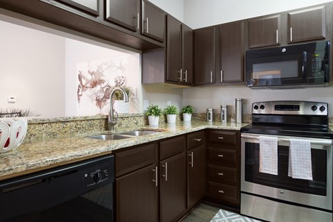 A kitchen with brown cabinets and black appliances.