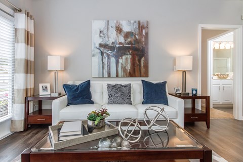 A living room with a white couch, a coffee table, and a large painting on the wall.