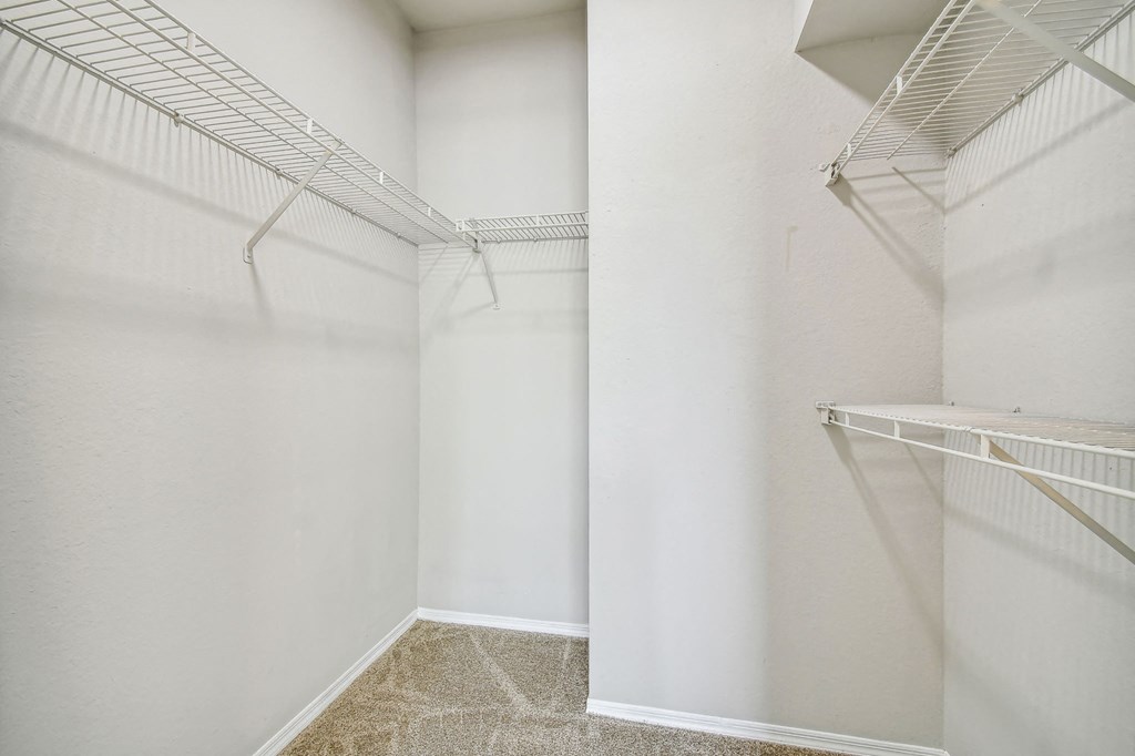 a walk in closet with white walls and mirrored closets