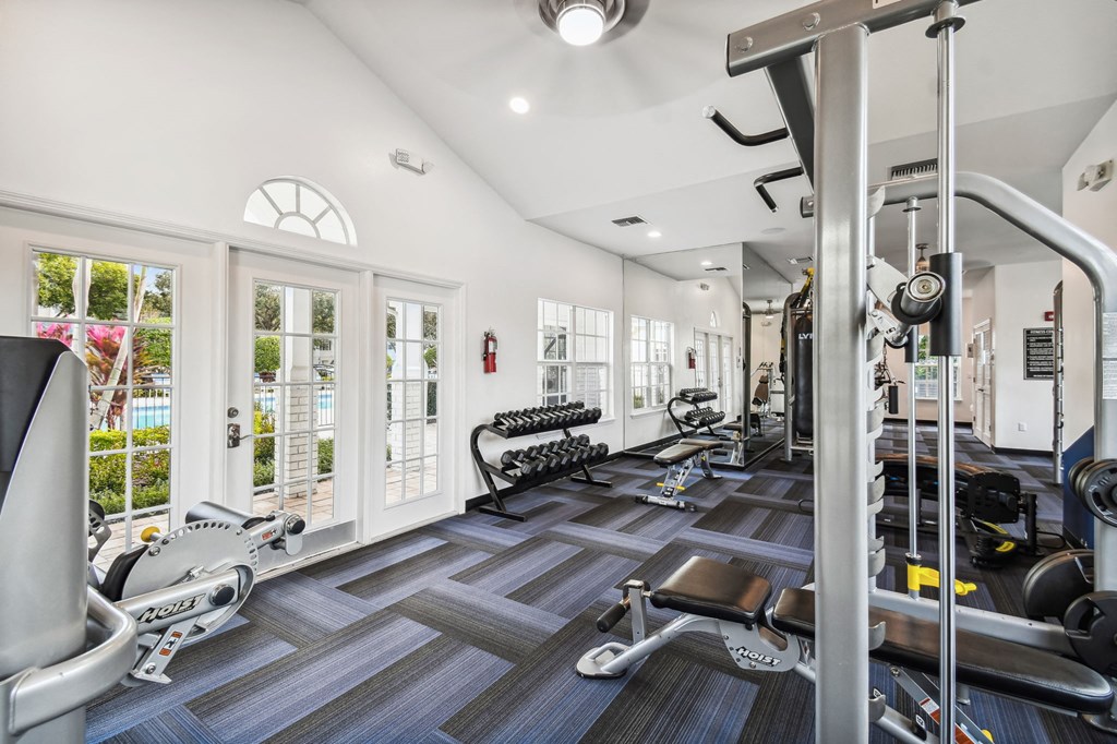 Baldwin Park, FL Apartments - Infinity off Baldwin Park - Fitness Center with Machines, Weights, Large Windows with View of Pool Area, and Large Mirror