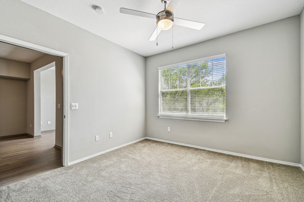 an empty room with a window and a ceiling fan
