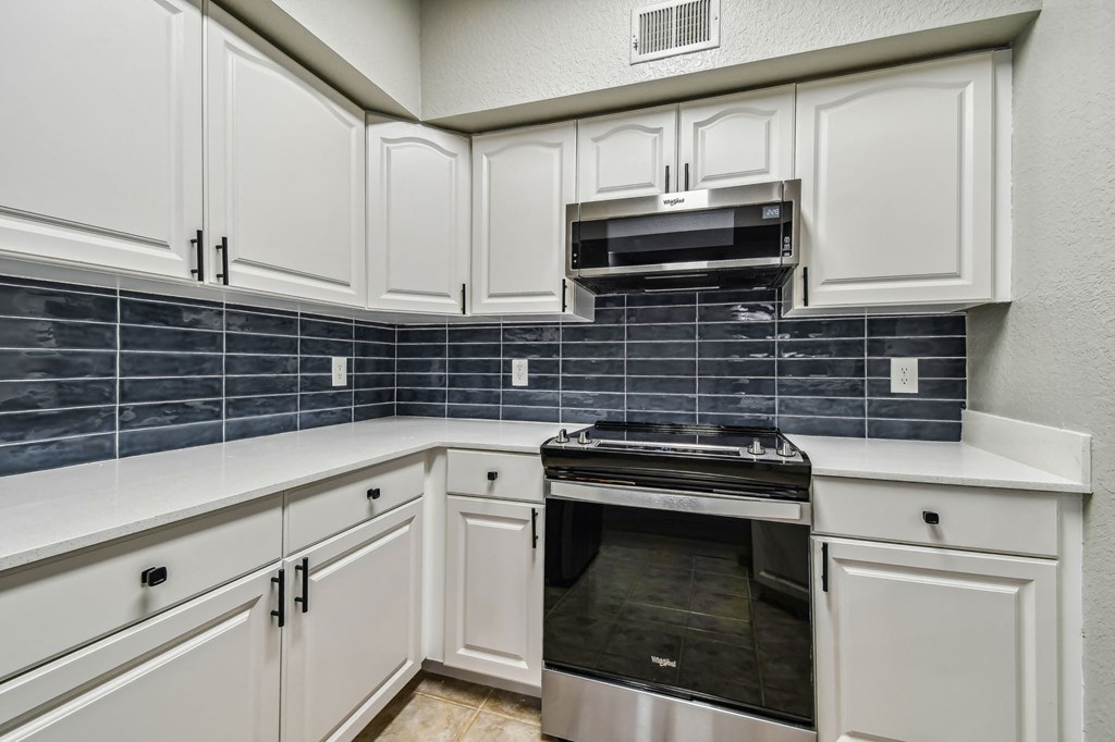 a kitchen with white cabinets and black and white appliances