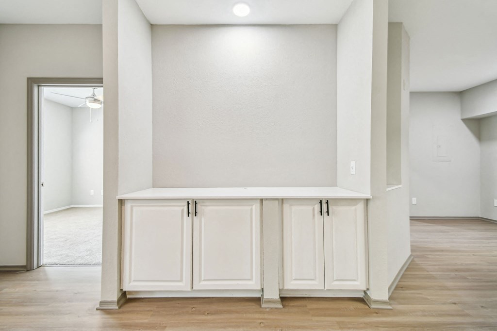 an empty living room with white cabinets and a white wall