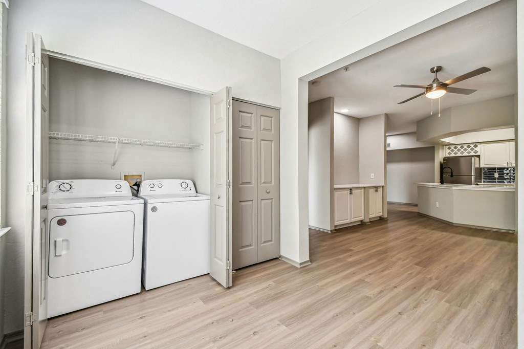 a renovated living room and laundry room with white appliances and a ceiling fan
