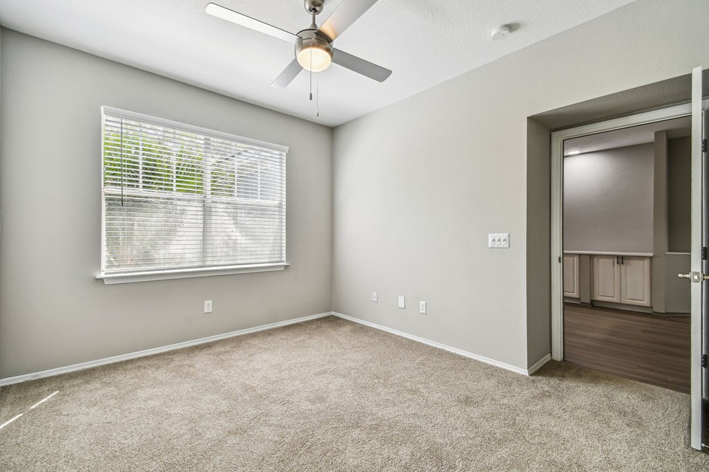 an empty room with a large window and a ceiling fan