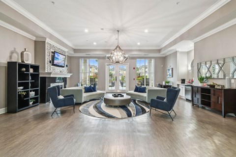 A spacious living room with a central circular rug and a television mounted on the wall.
