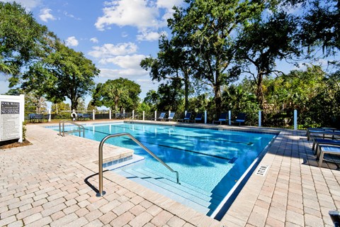 A pool surrounded by trees and a sign that says
