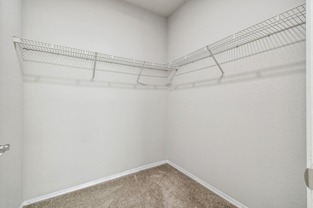 an empty closet in a room with white walls and carpet