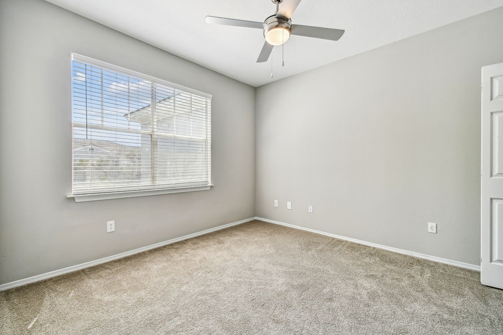 an empty room with a ceiling fan and a window