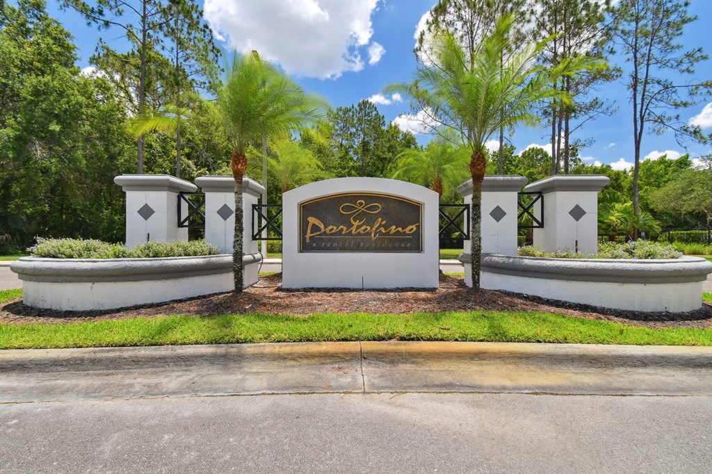 the sign at the entrance of a driveway to a subdivision with palm trees
