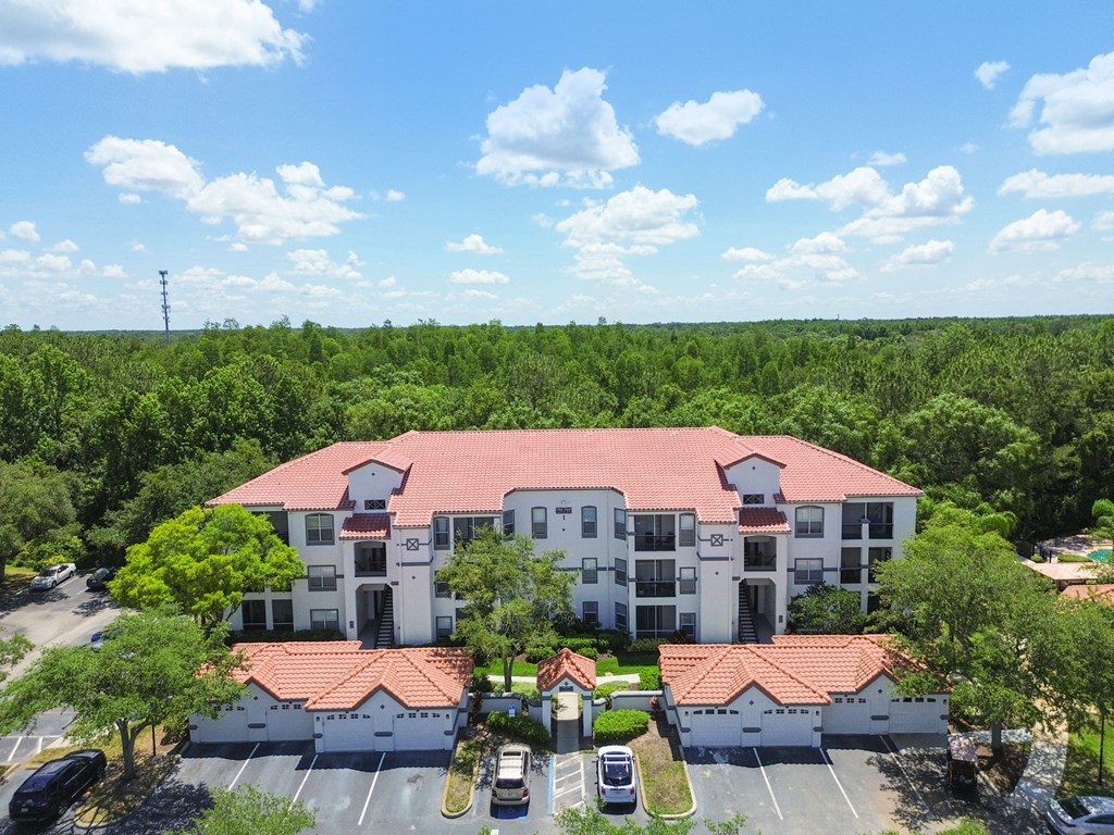an aerial view of a building with a parking lot and trees