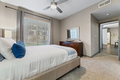 A bedroom with a large bed and a ceiling fan.