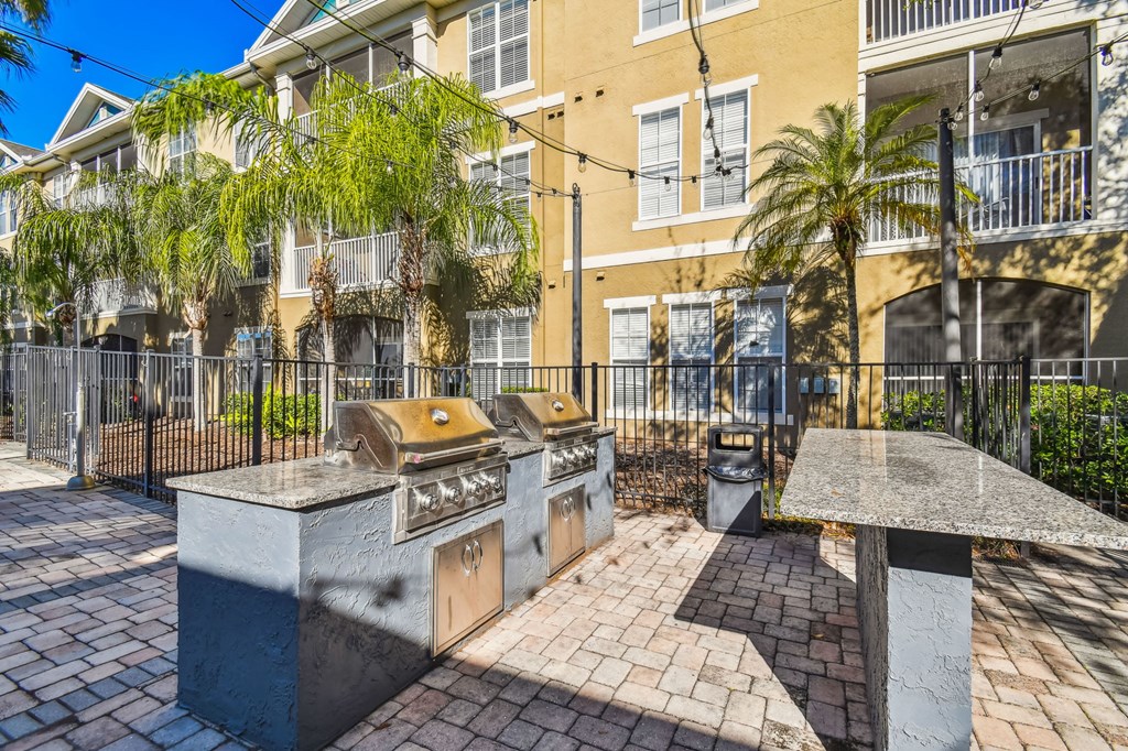 a backyard with a barbecue grill and a table with a trash can in front of a yellow