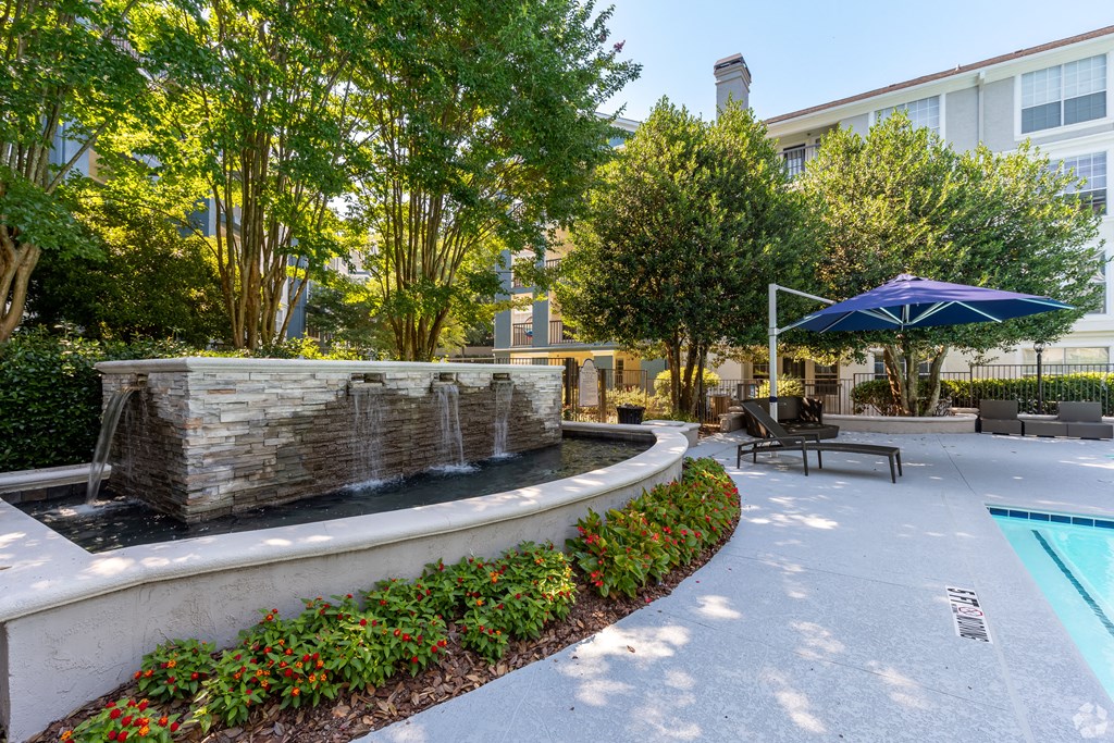 a fountain in a courtyard with trees and a building in the background