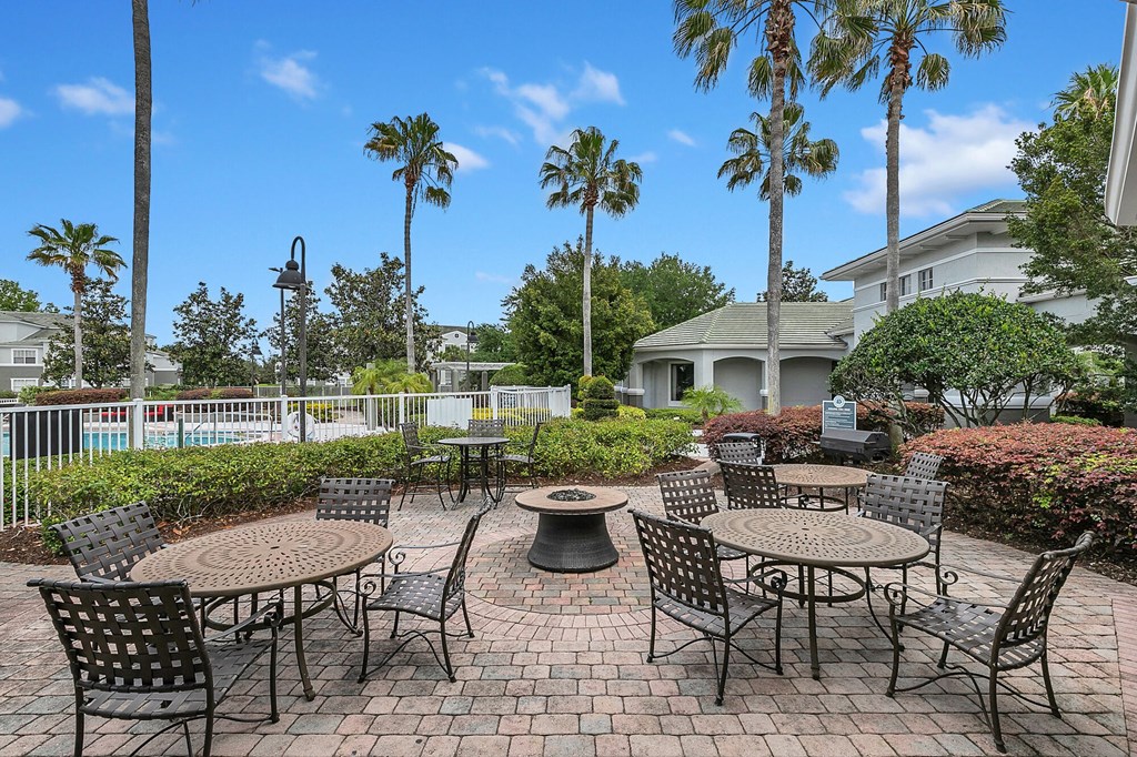 Winter Springs, FL Apartments - Outdoor Lounging Area With Chairs, Tables, BBQ Grills, Fire Pit, And Maintained Landscape.