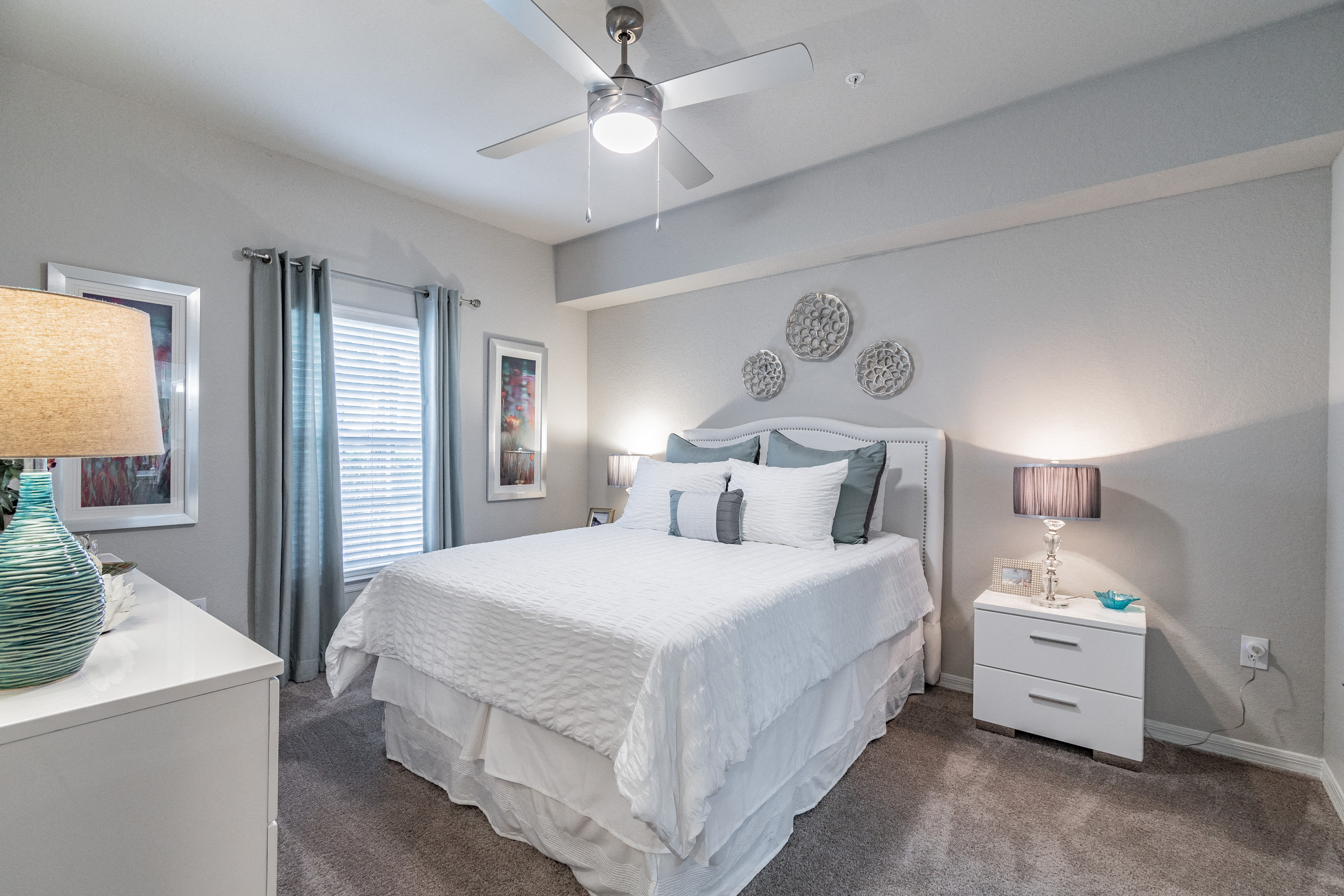 Dog-Friendly Apartments In Tampa, FL - Portofino - Spacious Bedroom With High Ceilings, Carpet Flooring, Expansive Window For Natural Sunlight, And Ceiling Fan.