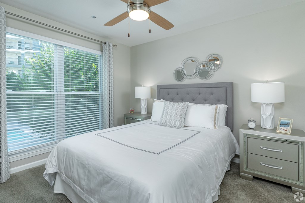 a bedroom with a large window and a ceiling fan