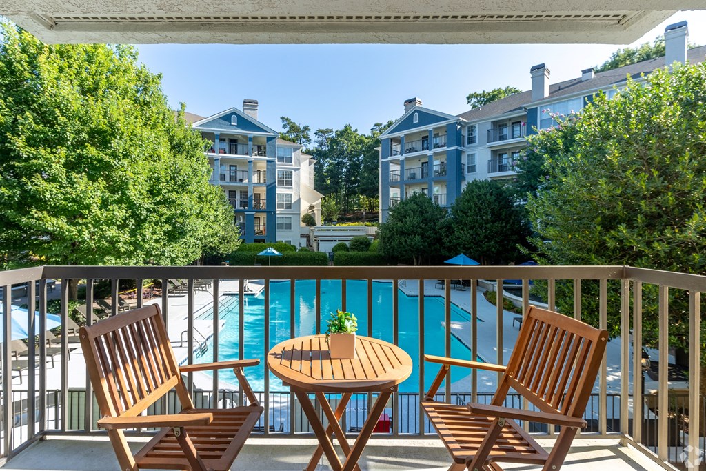 a balcony with a table and two chairs overlooks a swimming pool